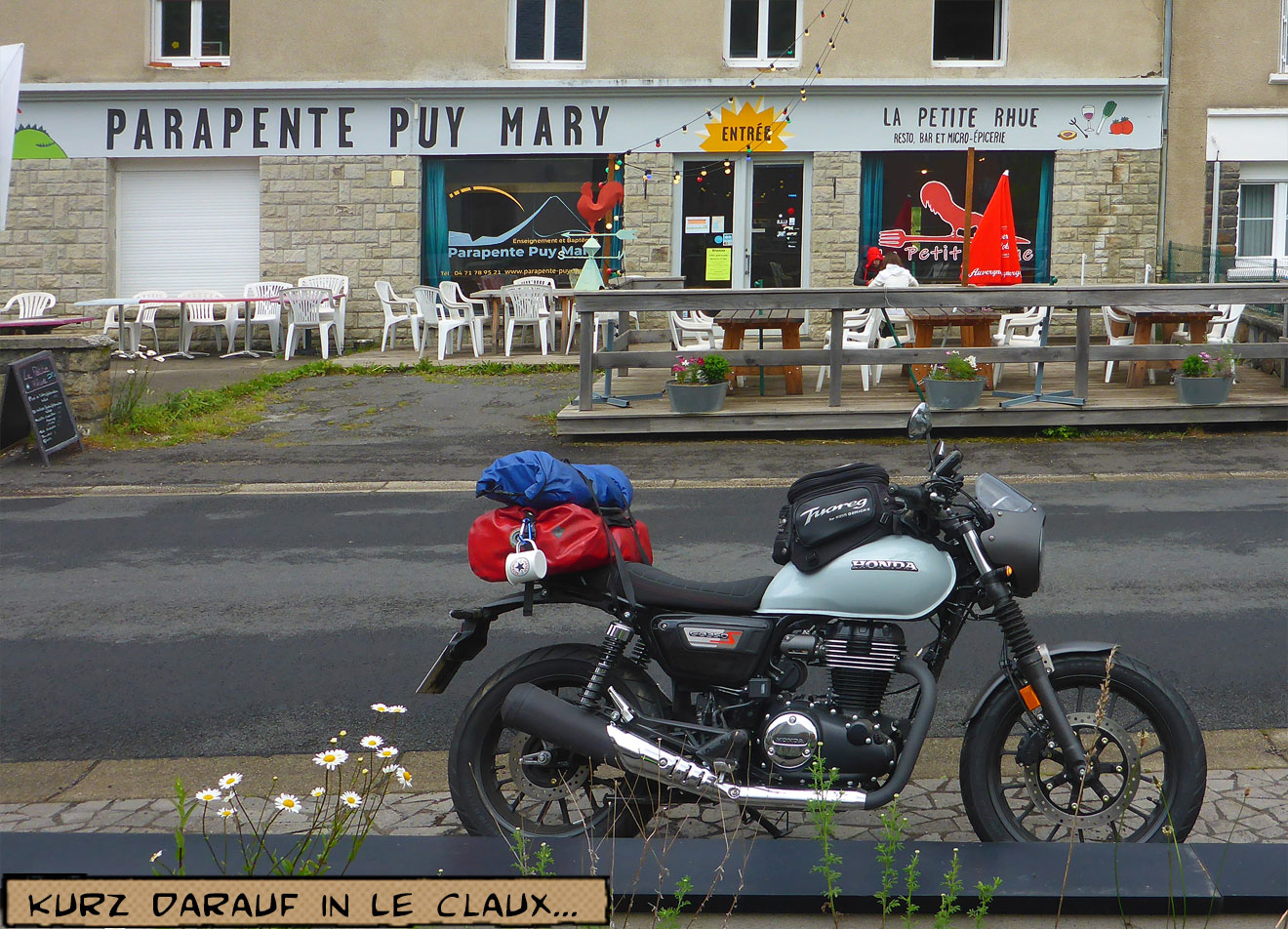 Ein Motorrad mit Reisegepäck steht vor einem Café