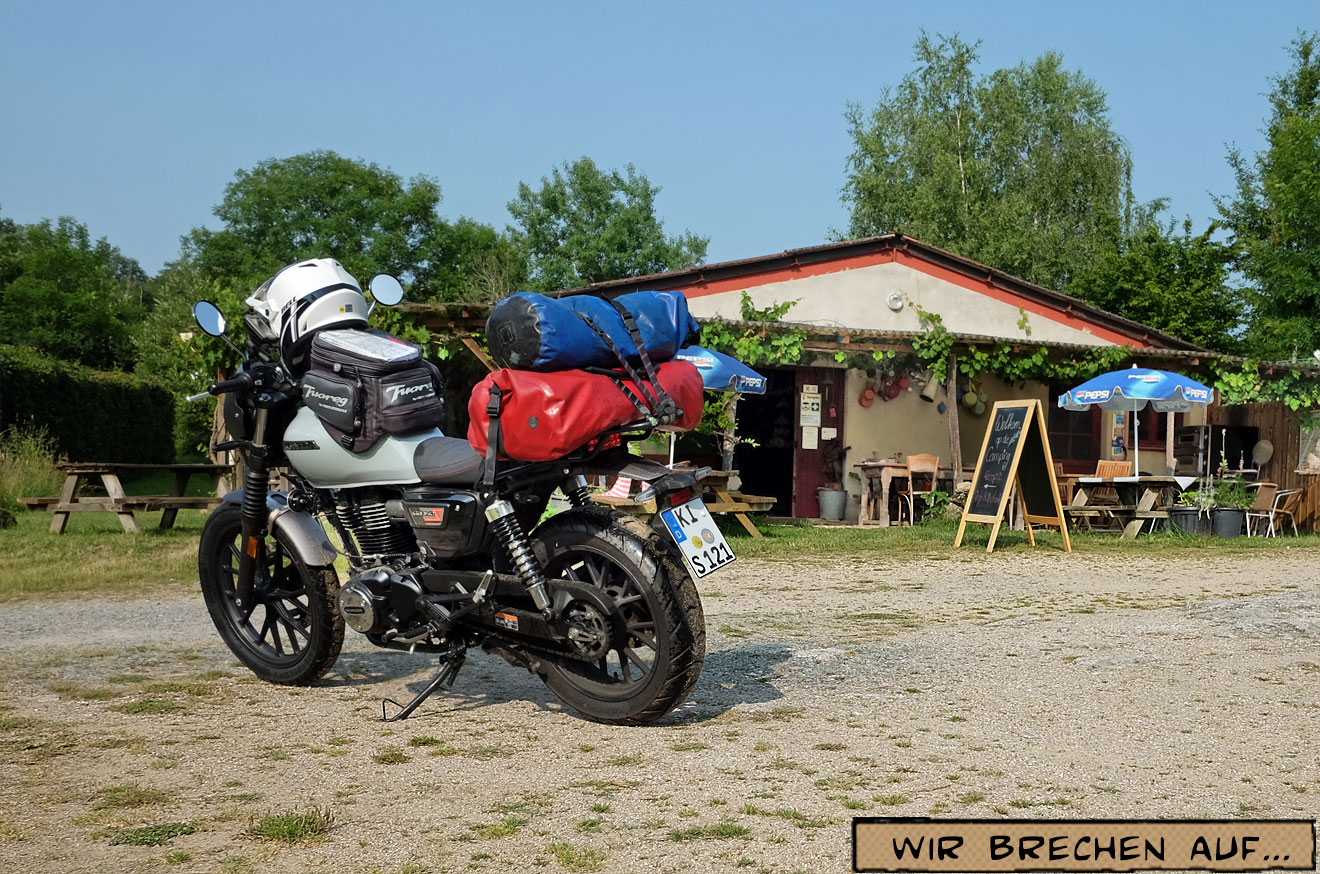 Ein Motorrad steht neben einem Zelt im GRAS